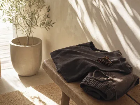Folded dark comfy clothes and a claw clip on a timber bench by a private front door