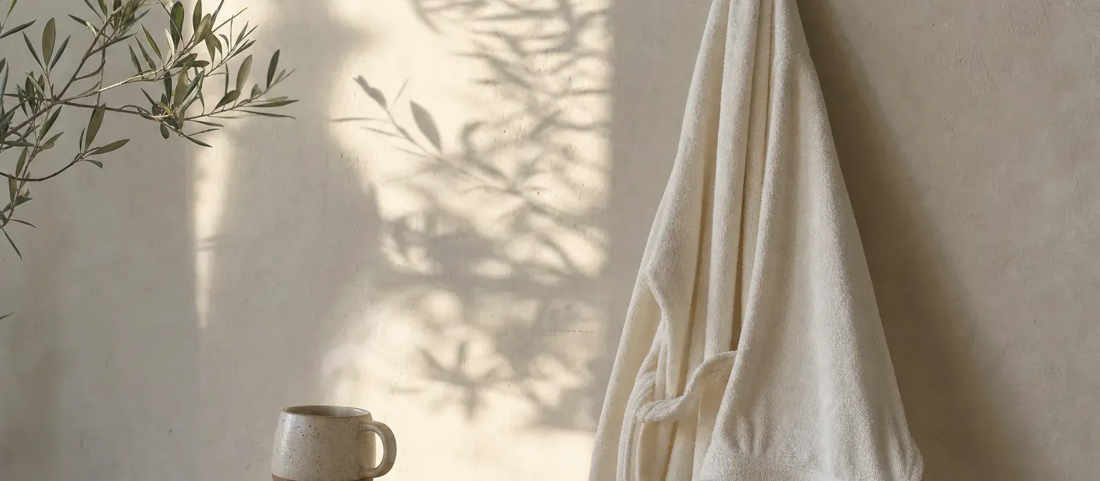 A soft robe hanging in morning light with a coffee below, easy spray tan aftercare