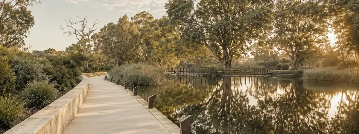 A lakeside path and timber bridge among gum trees at golden hour in Lakelands